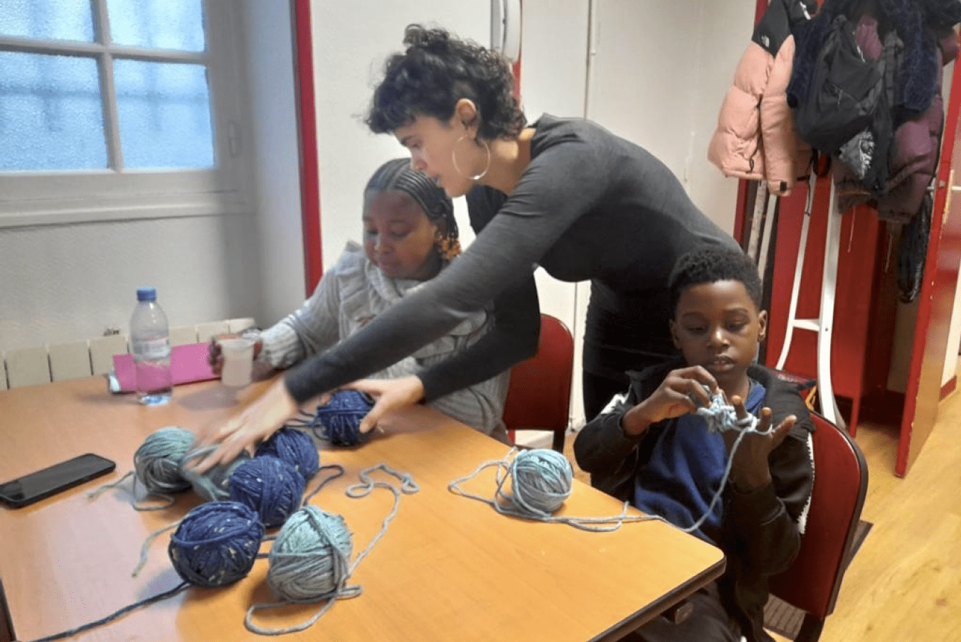 enfants et animateur pendant l'atelier de création artistique de fabrication de bracelets et autres objets à partir de produits recyclé, financée par la Réussite éducative, programme de l’état et de la ville de Paris
