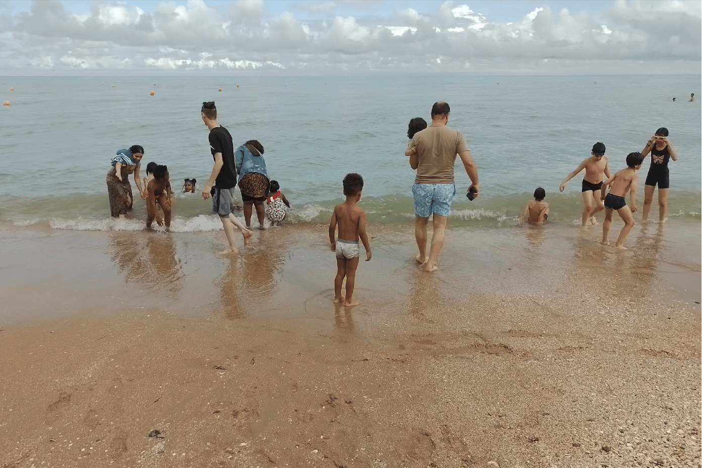 Familles de l'association et des CHU se baignant dans la mer lors du séjour à Cabourg fin juillet 2025