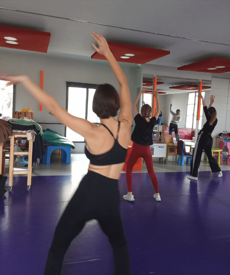 sport_sante_femmes-3 Groupe de femmes debout les bras en l'air pendant un cours pilates dans le cadre de l'activité Sport santé bien être pour les jeunes filles et jeunes femme