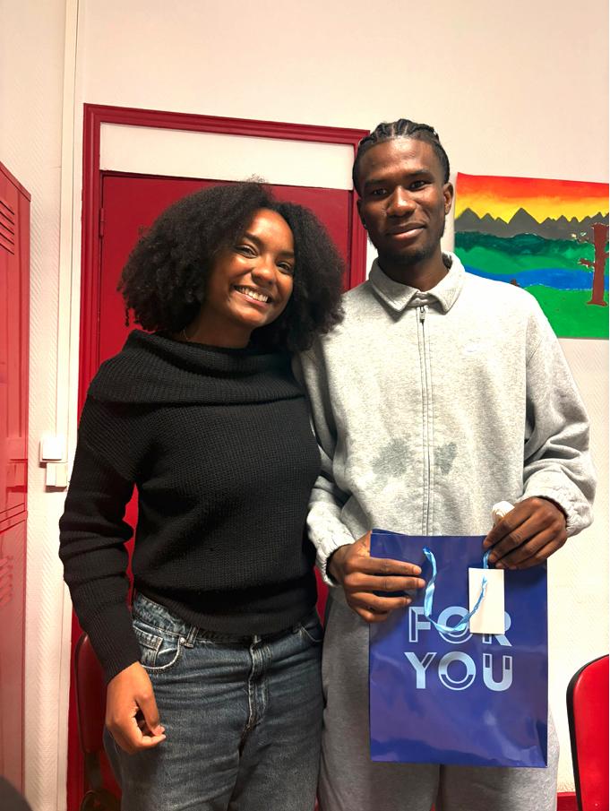 2 élèves souriants de l'atelier de conversation en français de l'association Axes Pluriels qui s'échangent des cadeaux de Noël pour décembre 2025