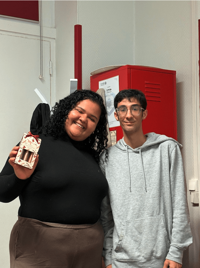 2 élèves souriants de l'atelier de conversation en français de l'association Axes Pluriels qui s'échangent des cadeaux de Noël pour décembre 2025