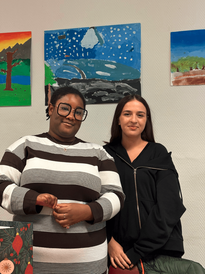 2 élèves souriants de l'atelier de conversation en français de l'association Axes Pluriels qui s'échangent des cadeaux de Noël pour décembre 2025
