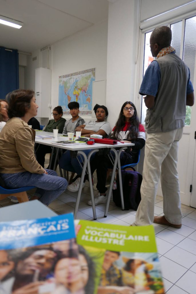 Groupe de migrants apprenant le français auprès d'un professeur