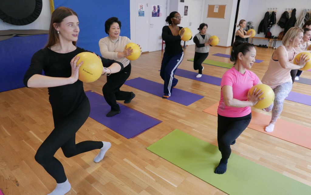 Femmes qui s'exercent avec un ballon et effectuent une rotation sur le côté pendant le cours de pilate