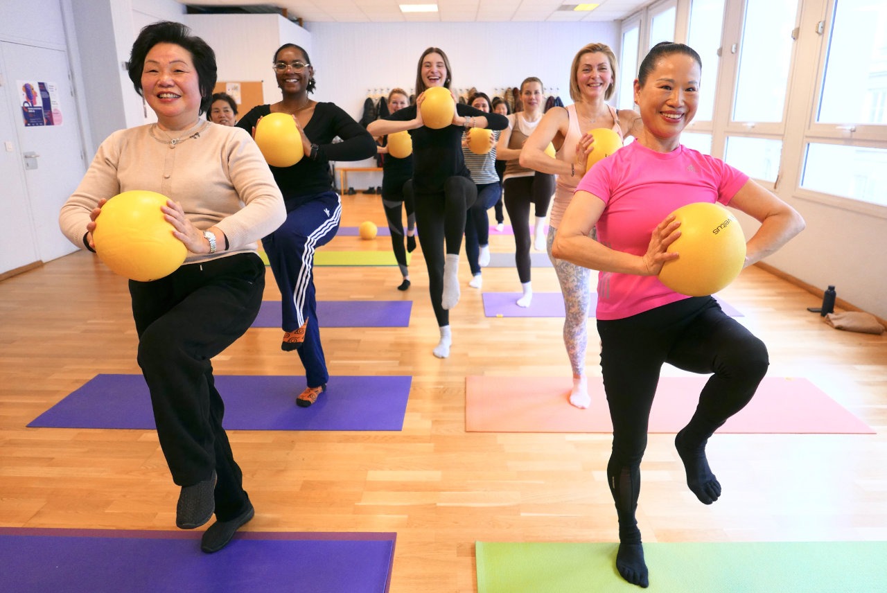 Femmes qui s'exercent avec un ballon debout sur une seule jambe pendant le cours de pilate