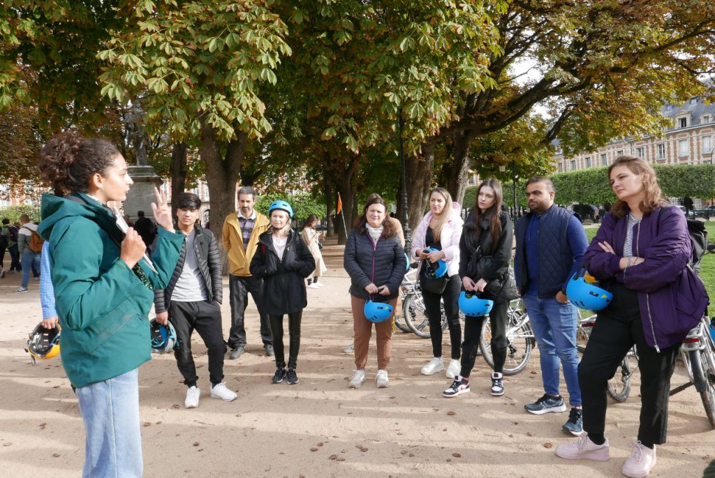 Groupe de migrants en cercle dans un parc écoutent les consignent avant la balade en vélo