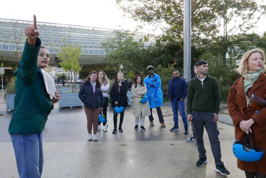 Groupe de migrants qui s'arrêtent devant un monument pendant la balade à vélo dans Paris