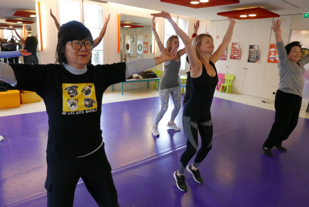 femmes qui dansent la zumba et lèvent les bras face à un miroir