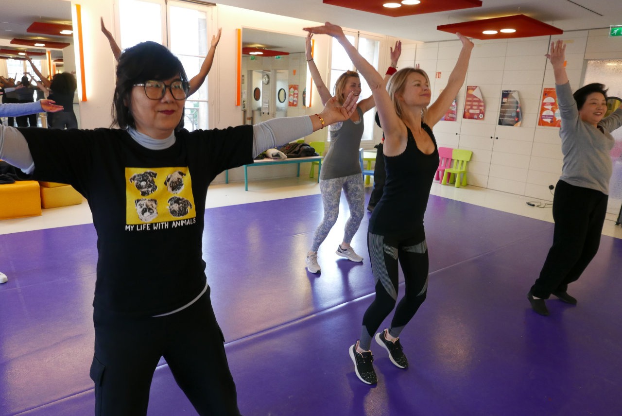 femmes qui dansent la zumba et lèvent les bras face à un miroir