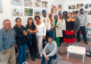Usagers de l'association posant pour une photo de groupe devant l'exposition photos visible à la médiathèque Françoise Sagan dans le 10e arrondissement de Paris
