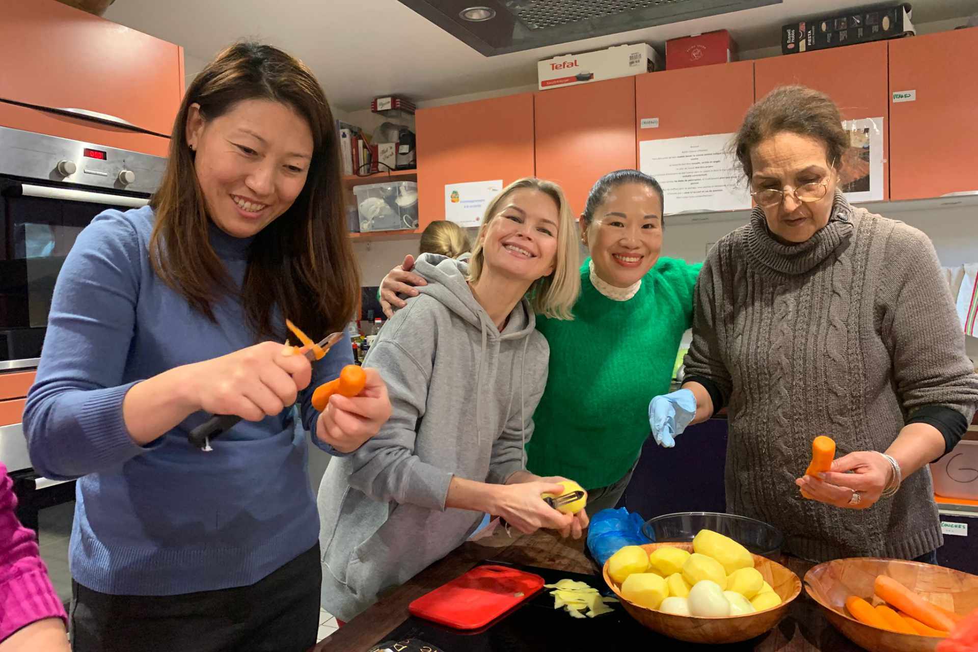 4 femmes usagères de l'association issues de différentes nationalités préparent un plat cuisine lors de l'atelier cuisine