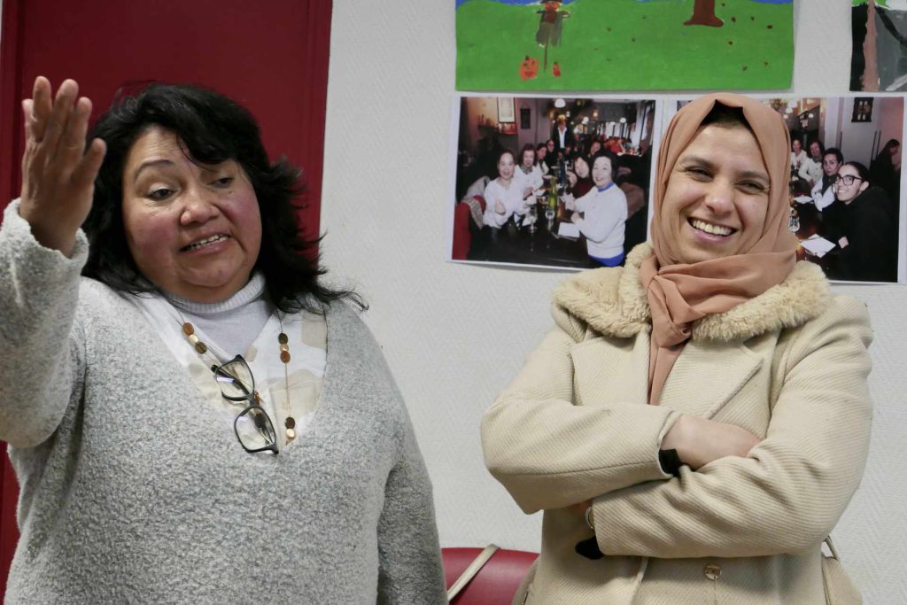deux femmes usagères de l'association sourient pendant qu'elles discutent avec d'autres personnes hors champ