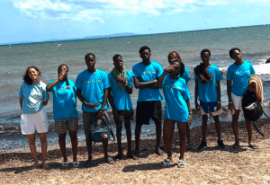 Groupe de jeunes usagers et leur animatrice de l'association portant le t-shirt bleu turquoise Axes pluriels sur la plage de Hyères