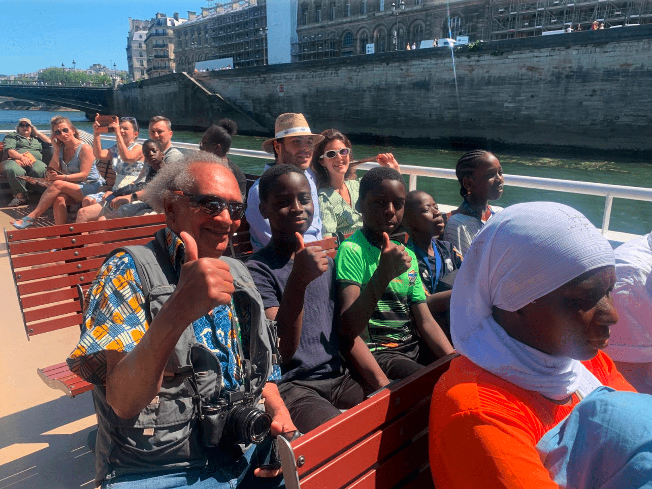 Groupe d'usagers de l'association assis dans un bateau mouche de Paris le pouce levé